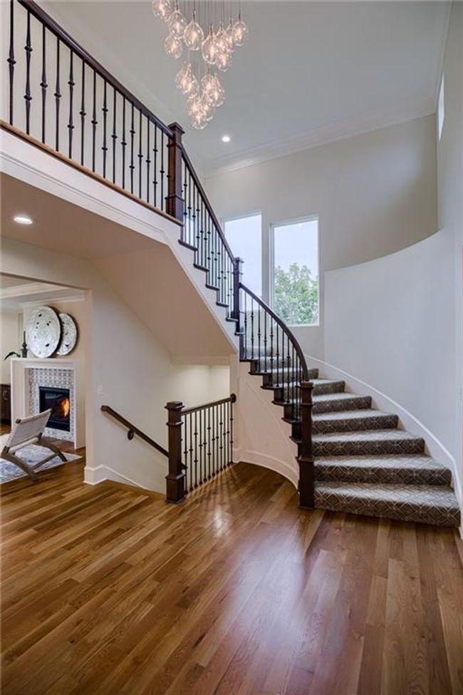 Staircase featuring ornamental molding, an inviting chandelier, wood-type flooring, and a fireplace | Image 24