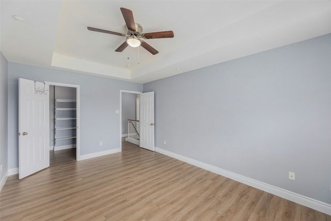 Unfurnished bedroom with a tray ceiling, light wood-style flooring, a closet, and a spacious closet | Image 21