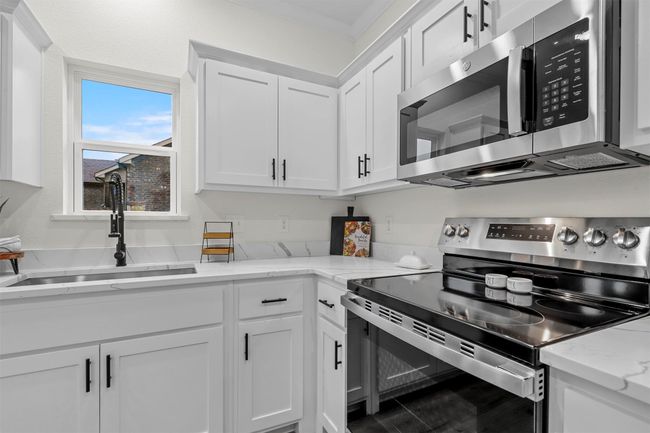 Kitchen with white cabinets, appliances with stainless steel finishes, sink, and light stone counters | Image 17