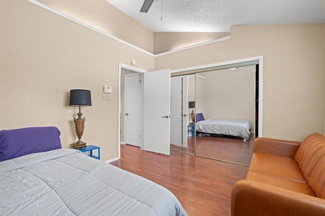 Bedroom with vaulted ceiling, wood finished floors, a closet, a ceiling fan, and a textured ceiling | Image 16