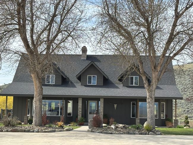 View of front facade with board and batten siding, a shingled roof, covered porch, and a chimney | Image 18