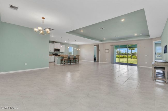 Living area featuring a tray ceiling, visible vents, recessed lighting, baseboards, and a notable chandelier | Image 4