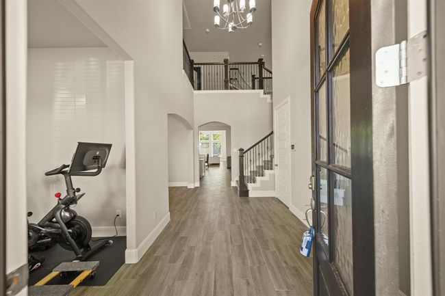 Step inside to a spacious entry hall with a view of the iron staircase and open-concept living beyond. | Image 4