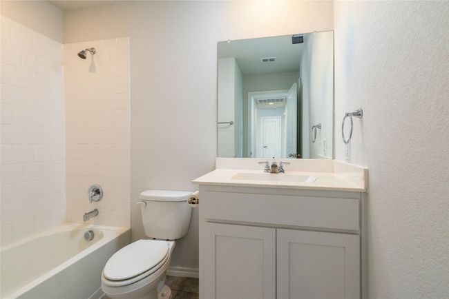 Full bathroom featuring toilet, vanity, bathtub / shower combination, and a textured wall | Image 30