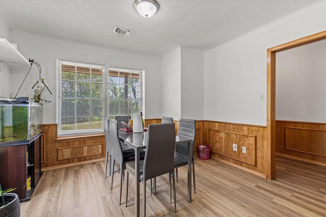 Dining space with wainscoting, a textured ceiling, light wood-style flooring, and wooden walls | Image 17
