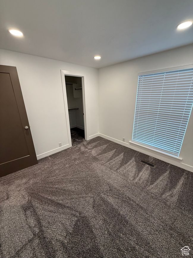 Unfurnished bedroom featuring recessed lighting, baseboards, dark carpet, and a walk in closet | Image 9