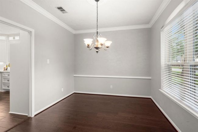 Dining room features rich wood flooring, a classic chandelier, and crisp white moldings that add timeless elegance, all with convenient direct access to the kitchen. | Image 6