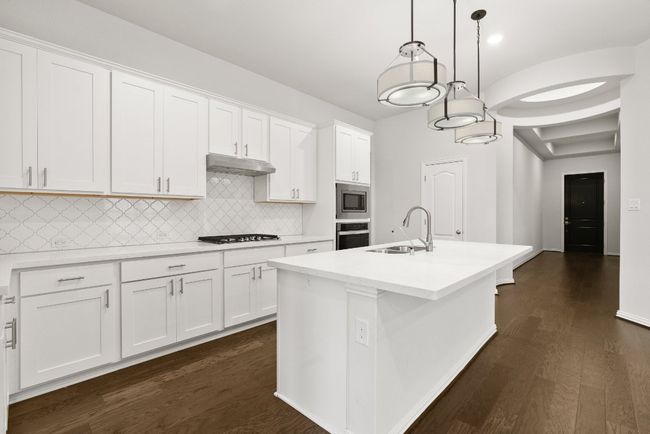Kitchen with white cabinetry, dark wood-style floors, light countertops, and lofted ceiling | Image 6