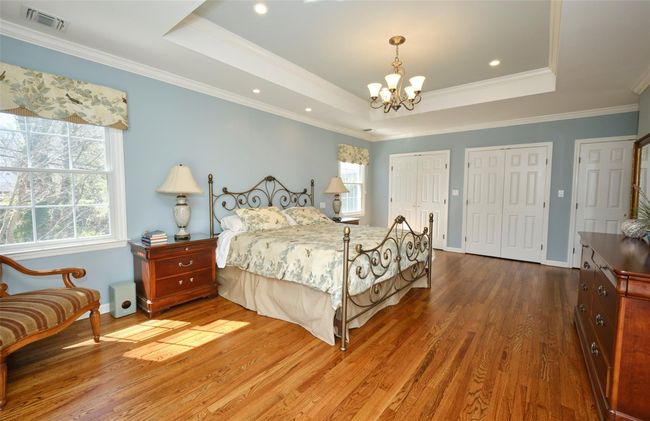 Bedroom featuring a chandelier, a tray ceiling, multiple closets, and visible vents | Image 22
