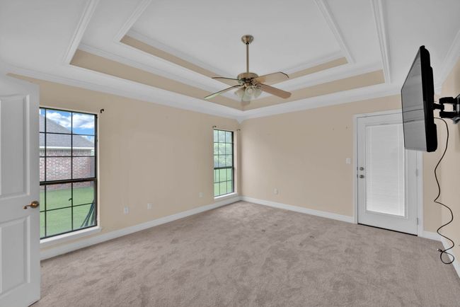 Empty room featuring a raised ceiling, ornamental molding, carpet flooring, and plenty of natural light | Image 17