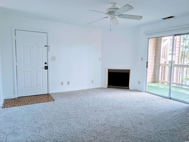 Unfurnished living room featuring carpet flooring, a fireplace, heating unit, and a ceiling fan | Image 4