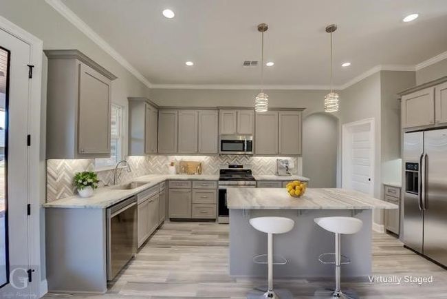 Kitchen featuring sink, gray cabinetry, hanging light fixtures, stainless steel appliances, and a kitchen island | Image 6