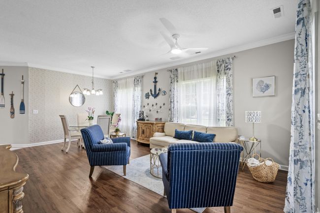 Living area featuring wallpapered walls, ornamental molding, wood finished floors, a chandelier, and baseboards | Image 11