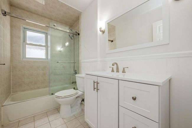 Full bathroom featuring vanity, tile patterned flooring, toilet, wainscoting, and bathtub / shower combination | Image 11