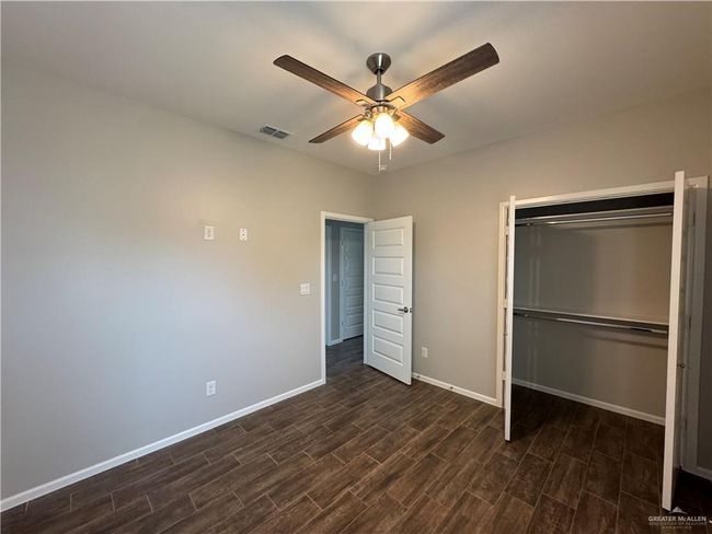 Unfurnished bedroom with dark wood-type flooring, baseboards, a closet, and ceiling fan | Image 15
