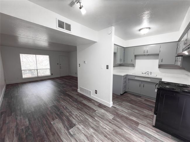 Kitchen with dark wood-type flooring, gray cabinets, black range oven, and sink | Image 5