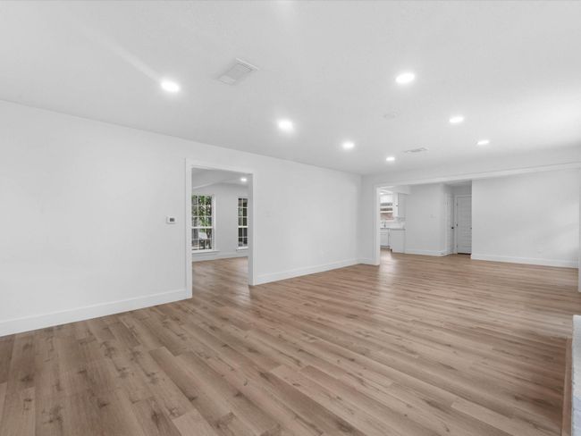 Spacious open-concept living area with sleek hardwood floors and recessed lighting, featuring a seamless flow into adjacent rooms and plenty of natural light. | Image 8