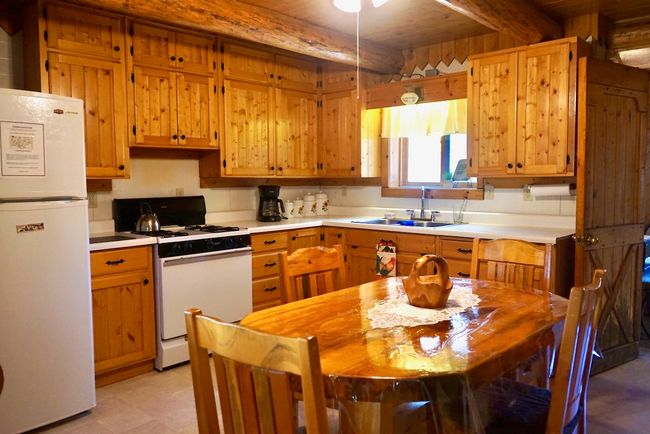 Kitchen with light countertops, white appliances, light floors, beam ceiling, and a sink | Image 27