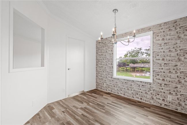 Unfurnished dining area with crown molding, a chandelier, wood finished floors, healthy amount of natural light, and vaulted ceiling | Image 13