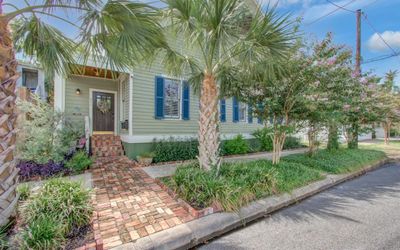 The stunning curb appeal beckons you to explore further, with lush palm trees and meticulously landscaped flowerbeds enhancing the property’s charm. A garage, conveniently accessible via the alley to the right, adds both functionality and ease of access to this exceptional home. | Image 2