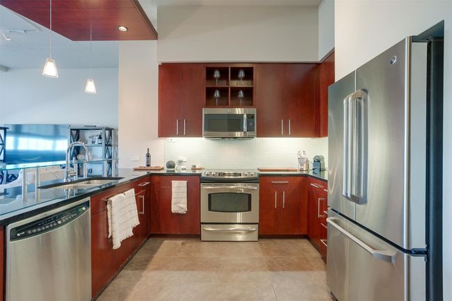 Kitchen featuring appliances with stainless steel finishes, tasteful backsplash, decorative light fixtures, open shelves, and light tile patterned floors | Image 12