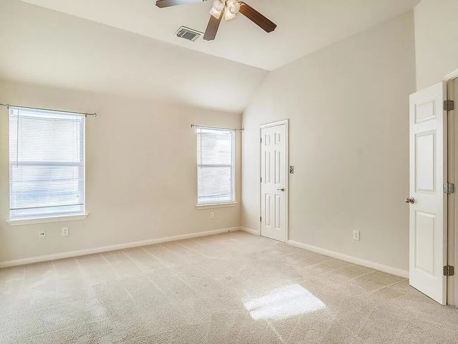 Unfurnished room featuring light colored carpet, ceiling fan, baseboards, healthy amount of natural light, and vaulted ceiling | Image 15