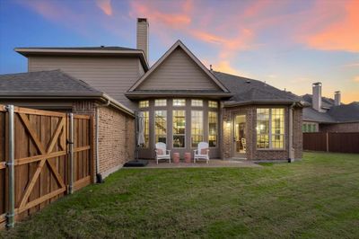 Back house at dusk featuring a lawn and a patio area | Image 2