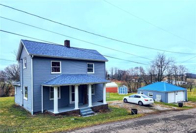 View of front facade with an outdoor structure, a garage, a porch, and a front yard | Image 1