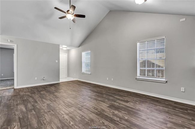 Unfurnished living room featuring a ceiling fan, high vaulted ceiling, and dark wood finished floors | Image 6