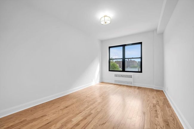 Spare room featuring radiator heating unit and light wood finished floors | Image 15