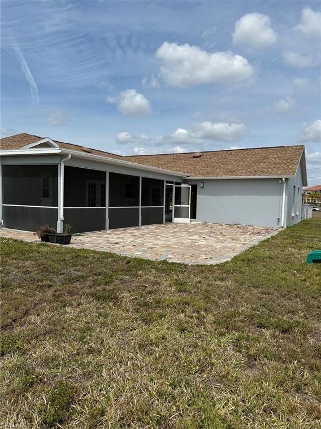 Back of house featuring a sunroom, a patio, a lawn, and stucco siding | Image 25