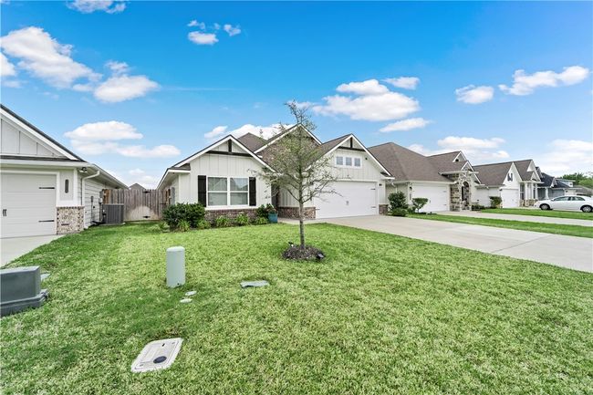 View of front of house with driveway, a front yard, board and batten siding, and central AC | Image 32