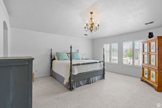 Bedroom with baseboards, visible vents, a chandelier, and light colored carpet | Image 36