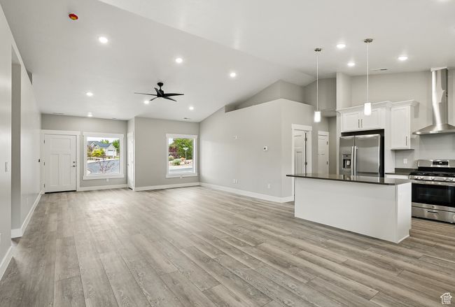 Unfurnished living room featuring light wood-type flooring, ceiling fan, baseboards, high vaulted ceiling, and recessed lighting | Image 17