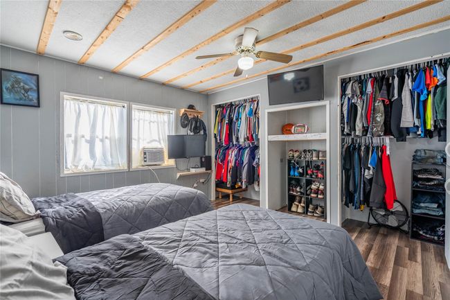 Bedroom with wood finished floors, two closets, ceiling fan, and cooling unit | Image 12