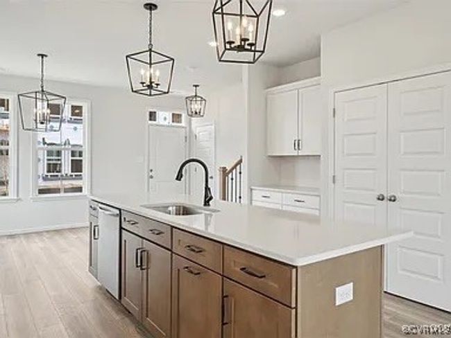 Kitchen with a chandelier, light wood-type flooring, dishwasher, light countertops, and recessed lighting | Image 10