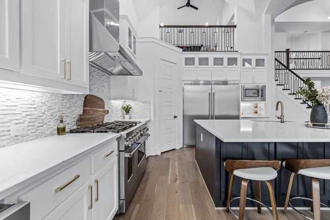 Kitchen with tasteful backsplash, built in appliances, wall chimney exhaust hood, sink, and light hardwood / wood-style floors | Image 13