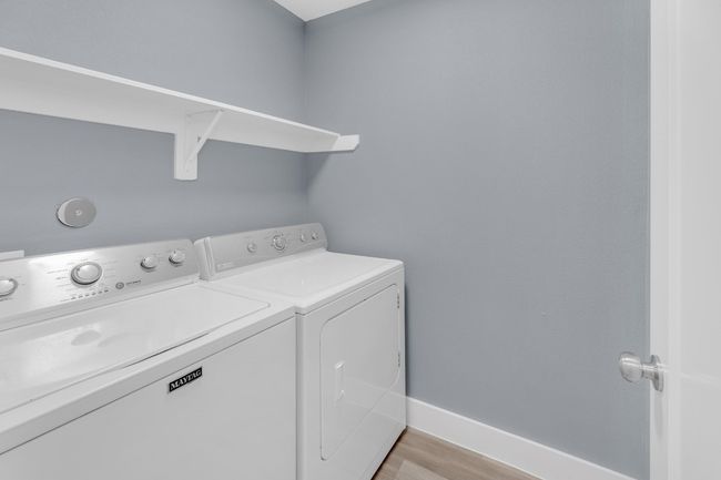 Clothes washing area with baseboards, washer and dryer, light wood-style floors, and laundry area | Image 22