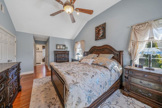 Bedroom with multiple windows, lofted ceiling, visible vents, and wood finished floors | Image 16