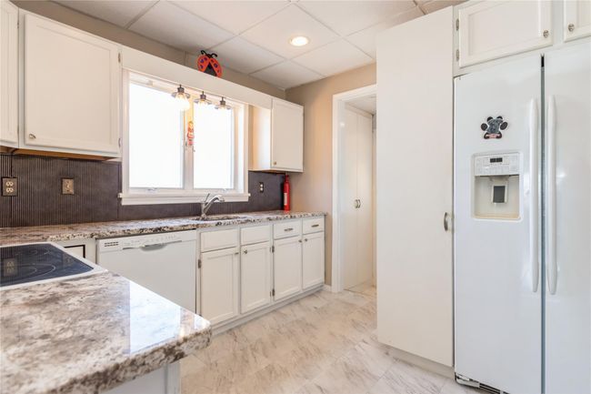 White cabinets and granite counters enhance the kitchen. | Image 5