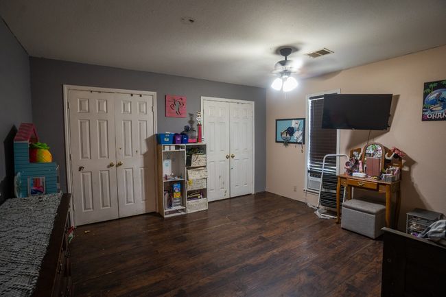 Bedroom featuring multiple closets, dark wood finished floors, and ceiling fan | Image 12