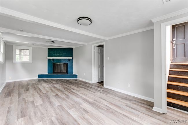 Unfurnished living room featuring crown molding, stairs, light wood-style flooring, and a fireplace | Image 16