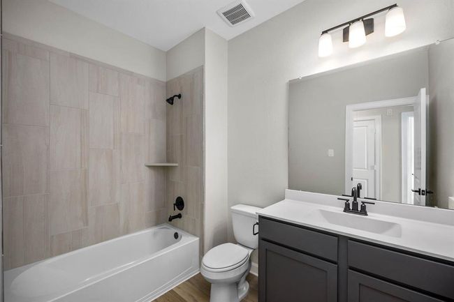 Step into the secondary bathroom, where a sleek vanity and mirror create a polished look, and the tub-shower combo ensures versatility for bathing preferences. With its thoughtful design and efficient layout, this bathroom offers both functionality and comfort. | Image 8
