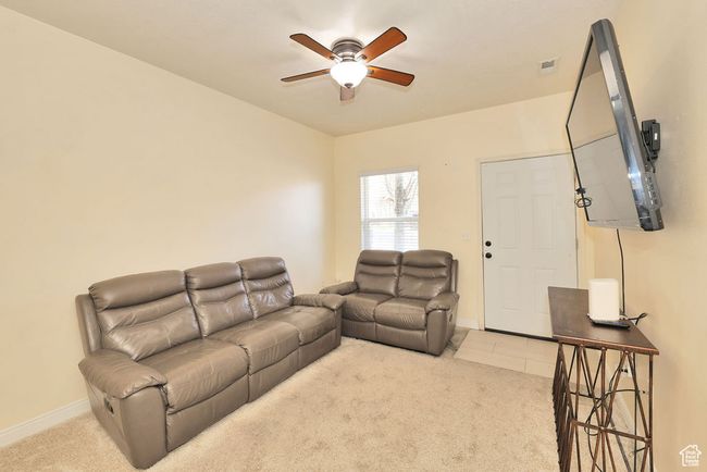 Carpeted living room with visible vents, baseboards, and ceiling fan | Image 9