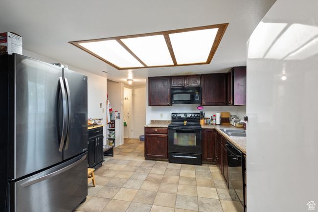 Kitchen with black appliances, light countertops, and dark brown cabinetry | Image 8