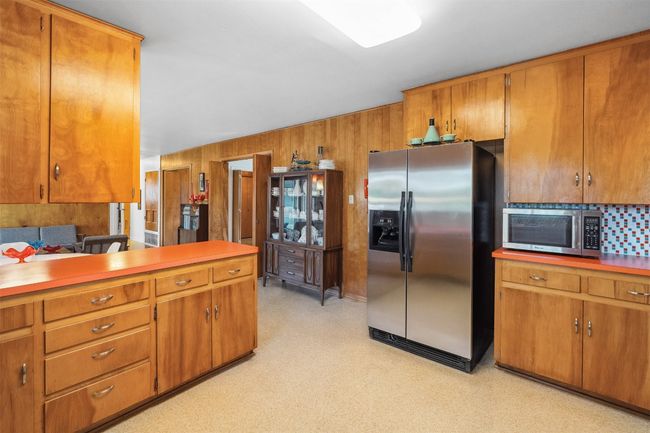 Kitchen featuring appliances with stainless steel finishes, wood walls and cabinets, and light floors | Image 17
