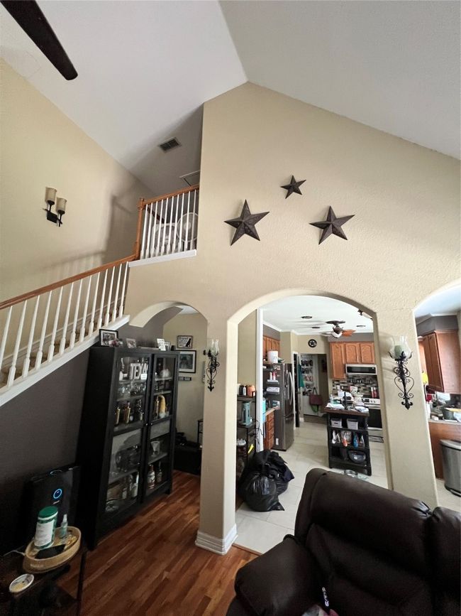 Living area featuring ceiling fan, arched walkways, light wood-style flooring, and high vaulted ceiling | Image 9