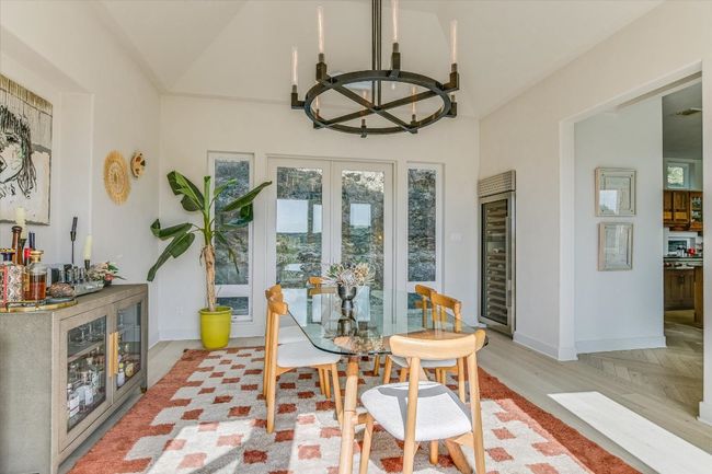 Dining space with beverage cooler, a chandelier, french doors, vaulted ceiling, and light wood-type flooring | Image 14