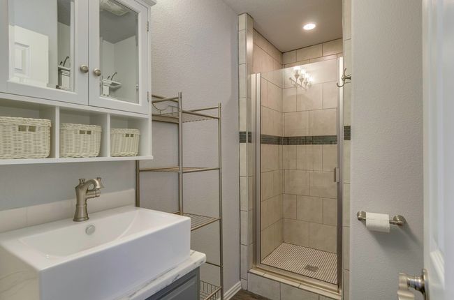 Bathroom featuring a shower stall, vanity, and a textured wall | Image 24