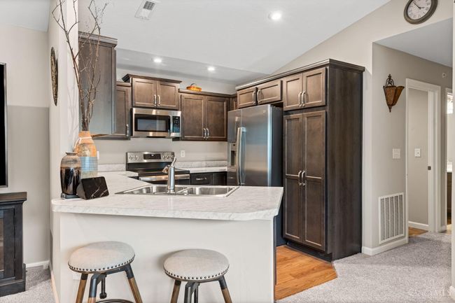 Kitchen with peninsula counter bar. Stainless steel appliances convey with condo. Laundry room located just past the kitchen on the left. | Image 11